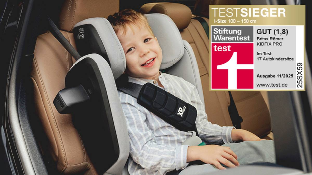 Ein lächelndes Kind sitzt in einem Britax Römer-Autositz. Das Bild hebt eine Testauszeichnung der Stiftung Warentest für den Sitz hervor, der mit „GUT (1,8)“ bewertet wurde.
