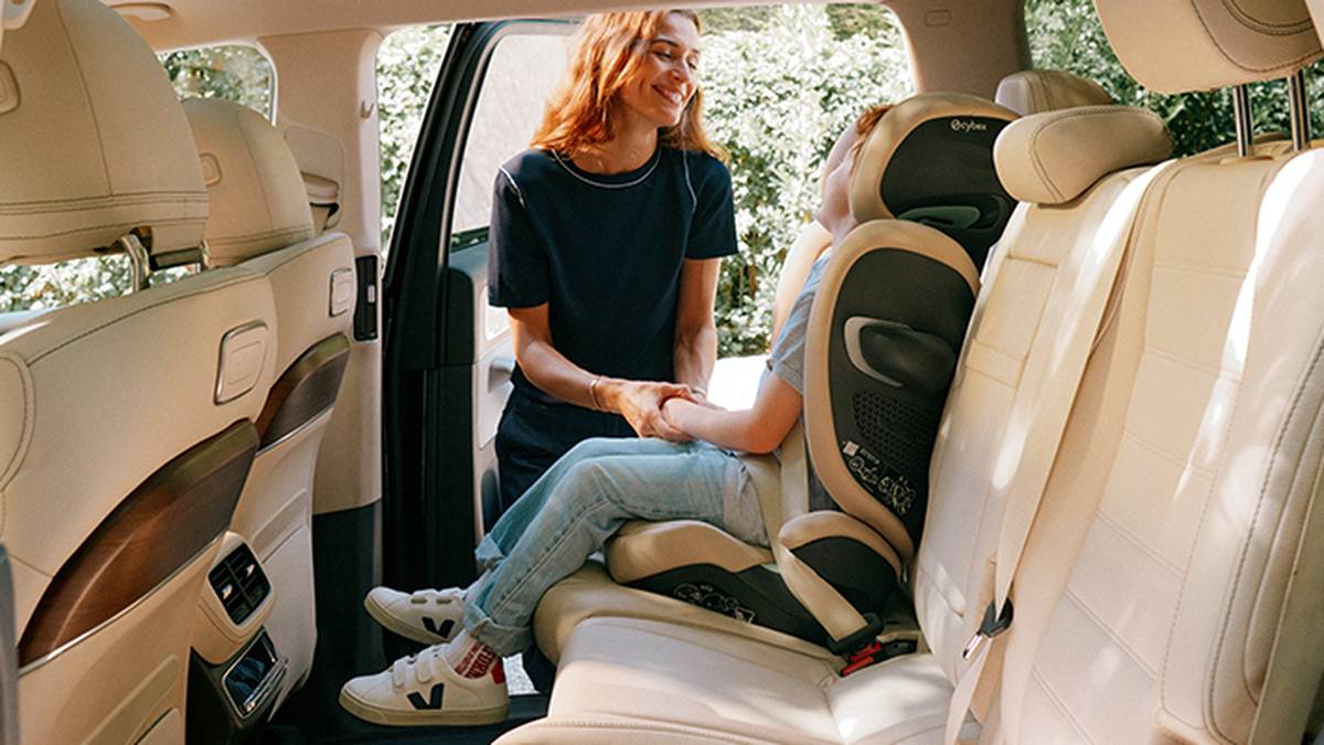 Frau hält die Hand eines Kindes, welches im Auto sitzt