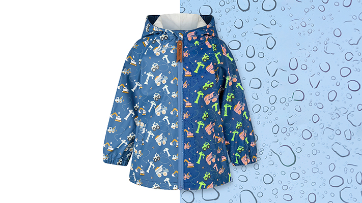 Wasserdichte Kinder-Regenjacke in Blau mit Kapuze und buntem Baustellenmotiv aus Baggern, Kränen und Fahrzeugen. Die Jacke wird vor einem Hintergrund mit Wassertropfen dargestellt, der die wetterfeste Funktion des Kleidungsstücks hervorhebt.