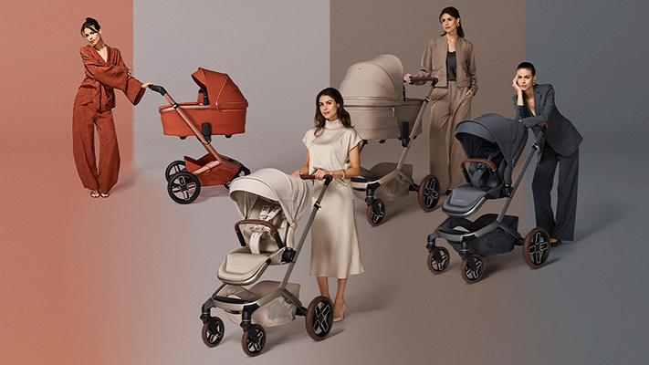 Vier elegant gekleidete Frauen posieren jeweils mit einem stylischen Kinderwagen in verschiedenen Farben vor einem farblich abgesetzten Hintergrund.