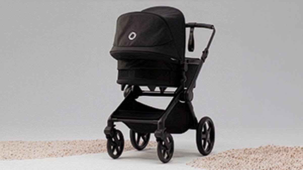 Ein schwarzer Kinderwagen mit Verdeck und vier großen Rädern vor einem schlichten zweifarbigen Hintergrund.