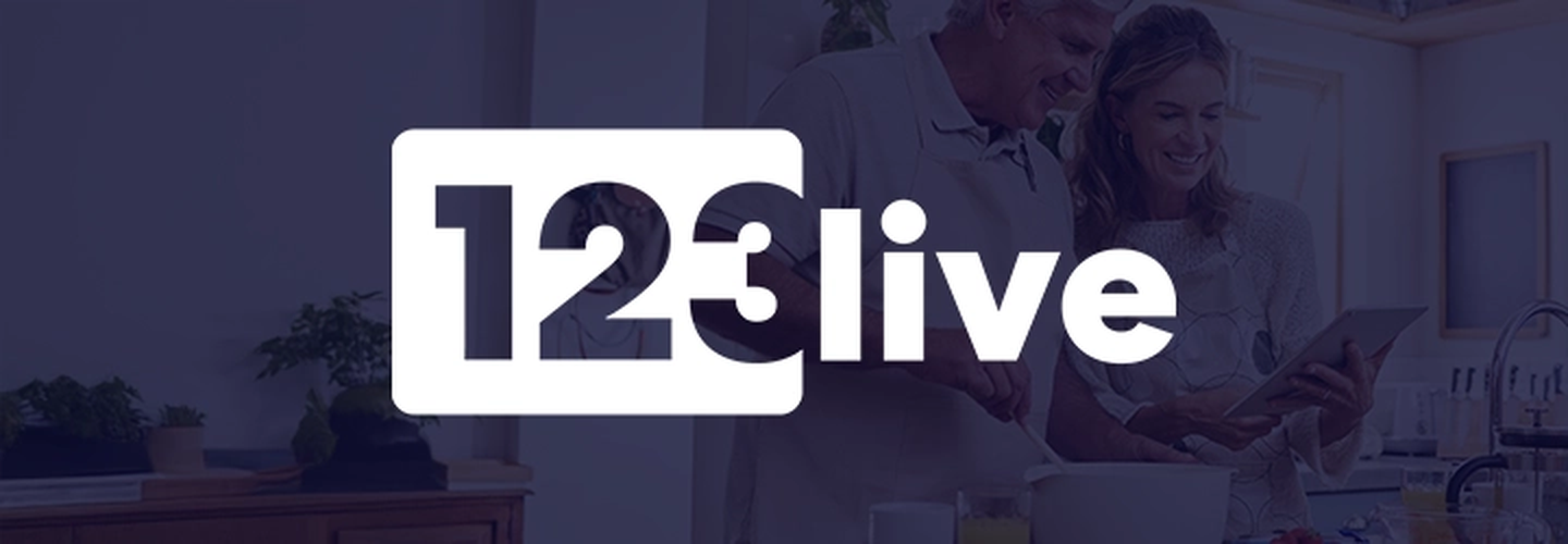 Älteres Ehepaar kocht in einer modernen Küche, lächelt, mit dem Text „123 live” auf der linken Seite.