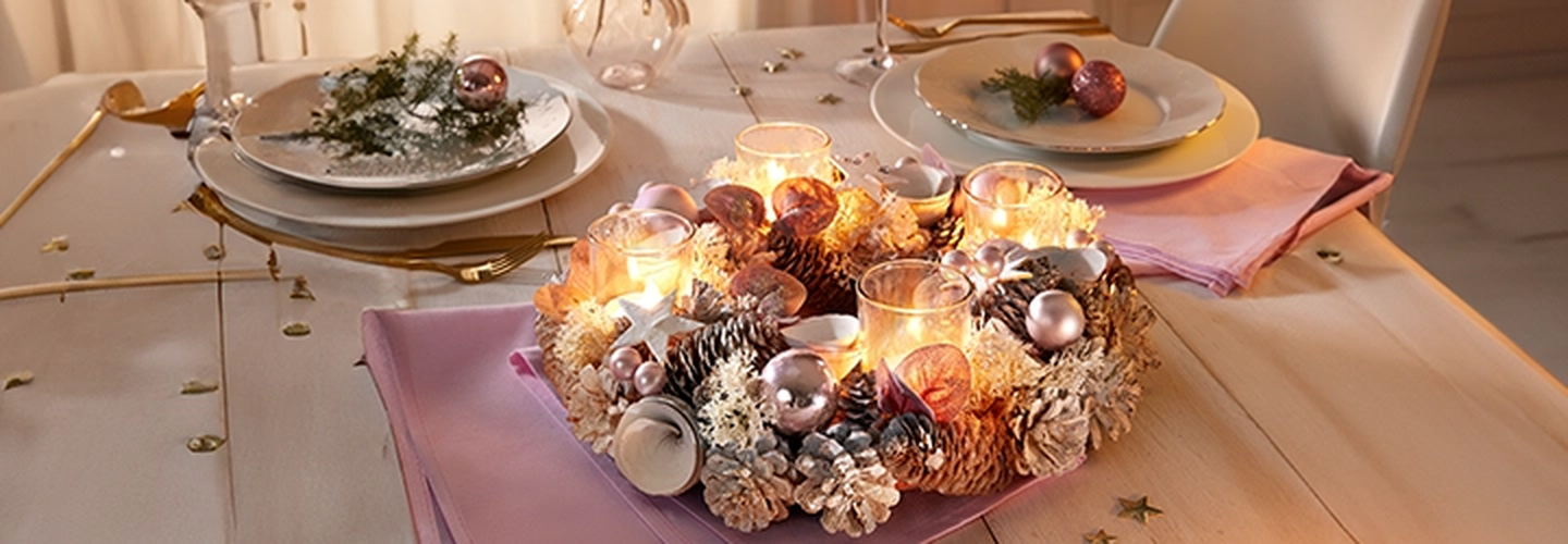 Festlich gedeckter Tisch mit Kerzenkranz, goldenem Besteck und Dekorationen. Stimmungsvolle Beleuchtung und elegante Servietten auf den Tellern.