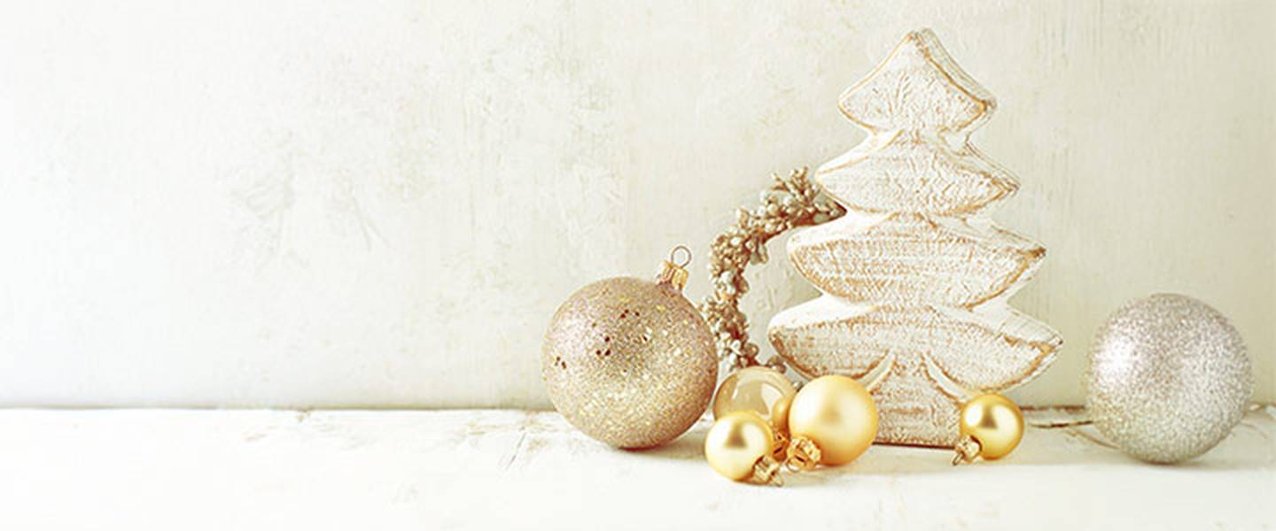 Hölzerner Weihnachtsbaum mit goldenem und silbernem Schmuck auf hellem Hintergrund.