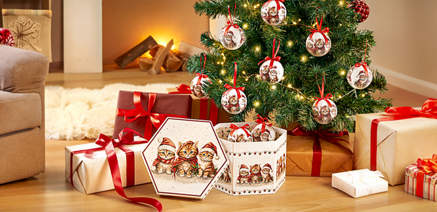 Weihnachtlich dekoriertes Wohnzimmer mit geschmücktem Weihnachtsbaum, Geschenken und Katzenmotiven vor einem gemütlichen Kamin.
