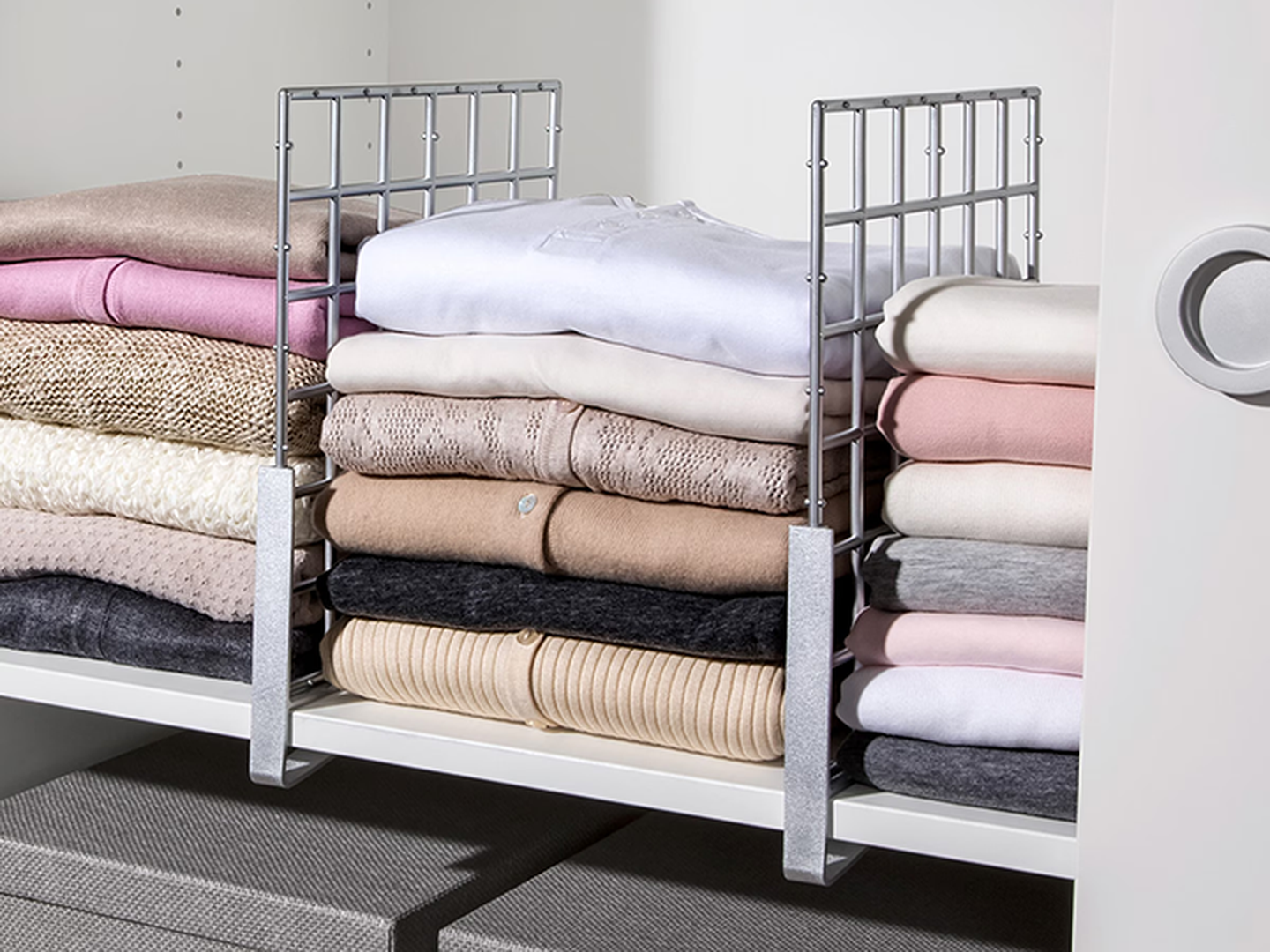 Aufnahme eines Kleiderschranks mit drei Stapeln an Oberteilen welche durch Kleiderschrank Organizer getrennt werden