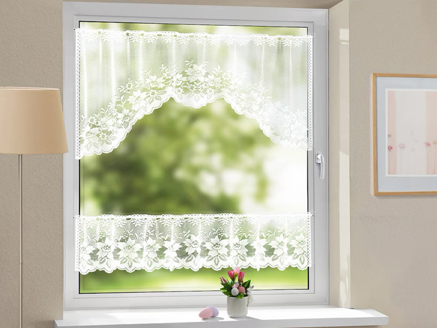 Fenster mit Spitzengardinen, die einen verschwommenen Blick ins Grüne draußen freigeben; eine Lampe, ein gerahmtes Bild und eine kleine Topfpflanze auf der Fensterbank.