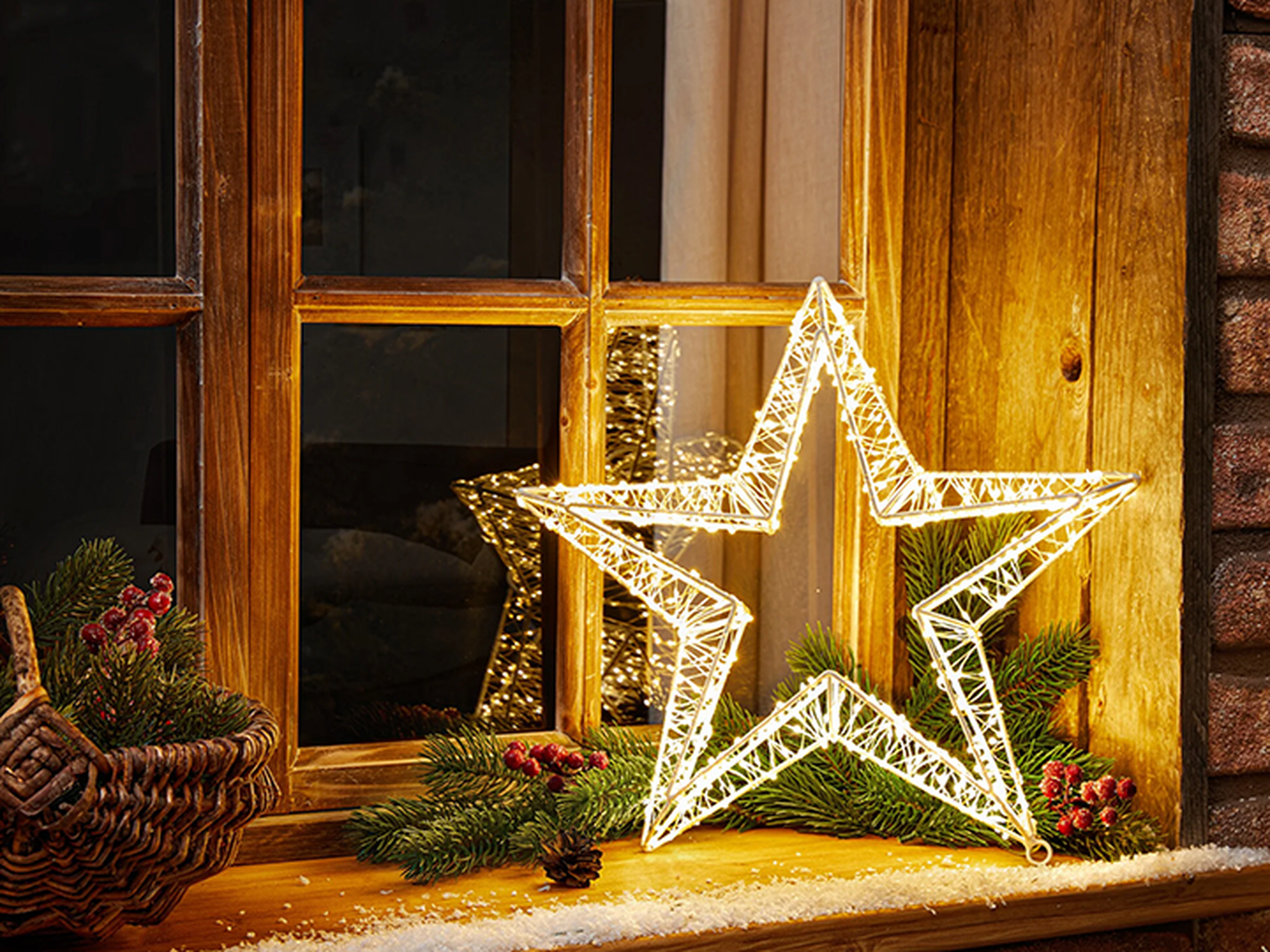 Ein LED Weihnachtsstern steht leuchtend vor einem Fenster.