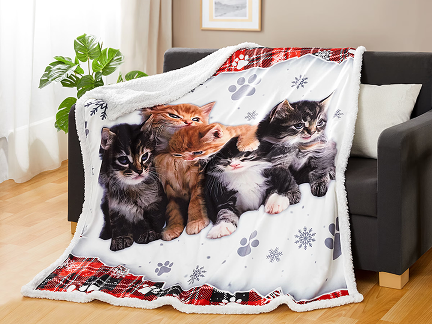 Auf einem dunklen Sofa liegt eine Kuscheldecke mit einem Katzen Motiv