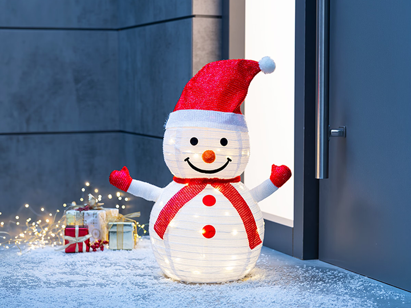 Ein weißer LED Schneemann steht vor einer grauen Haustüre