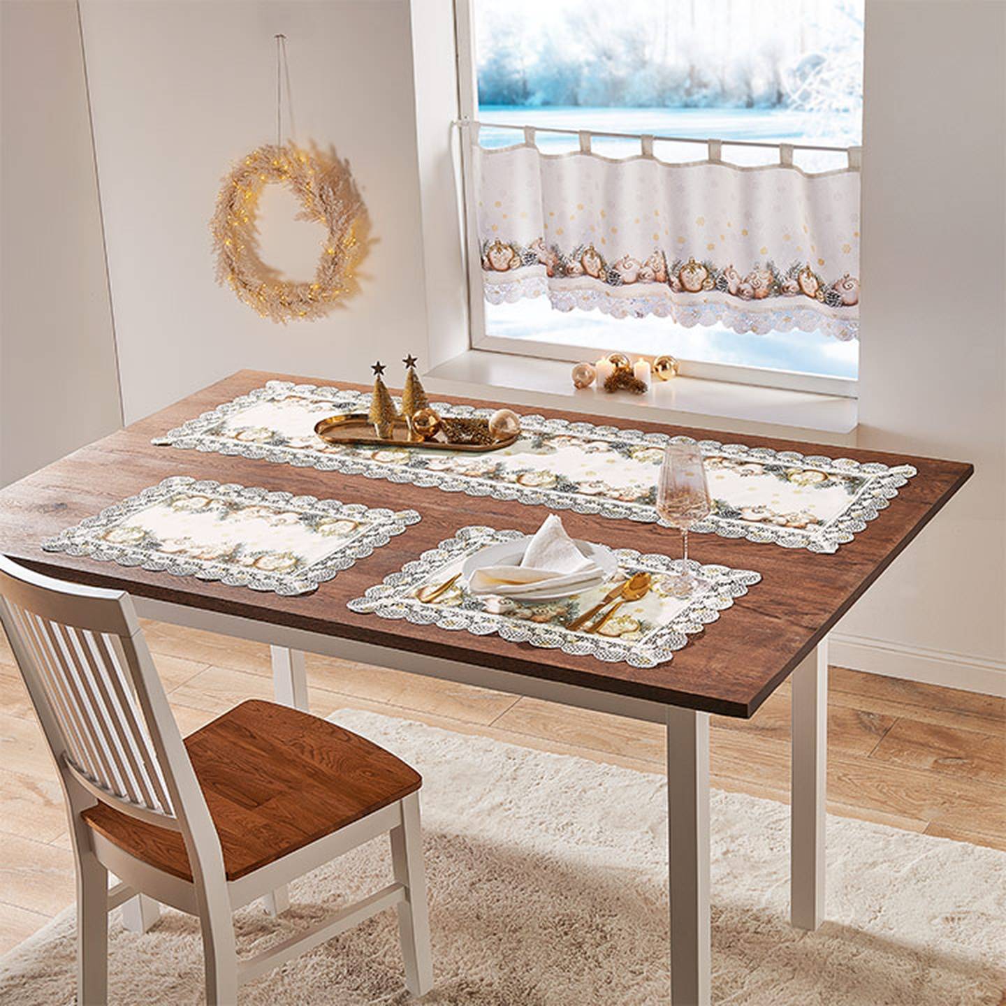 Ein festlich gedeckter Esstisch mit Platzsets, einem Gesteck aus goldenen Bäumchen, einem Glas Wein und einem weißen Stuhl steht in der Nähe eines Fensters mit dekorativen Vorhängen.