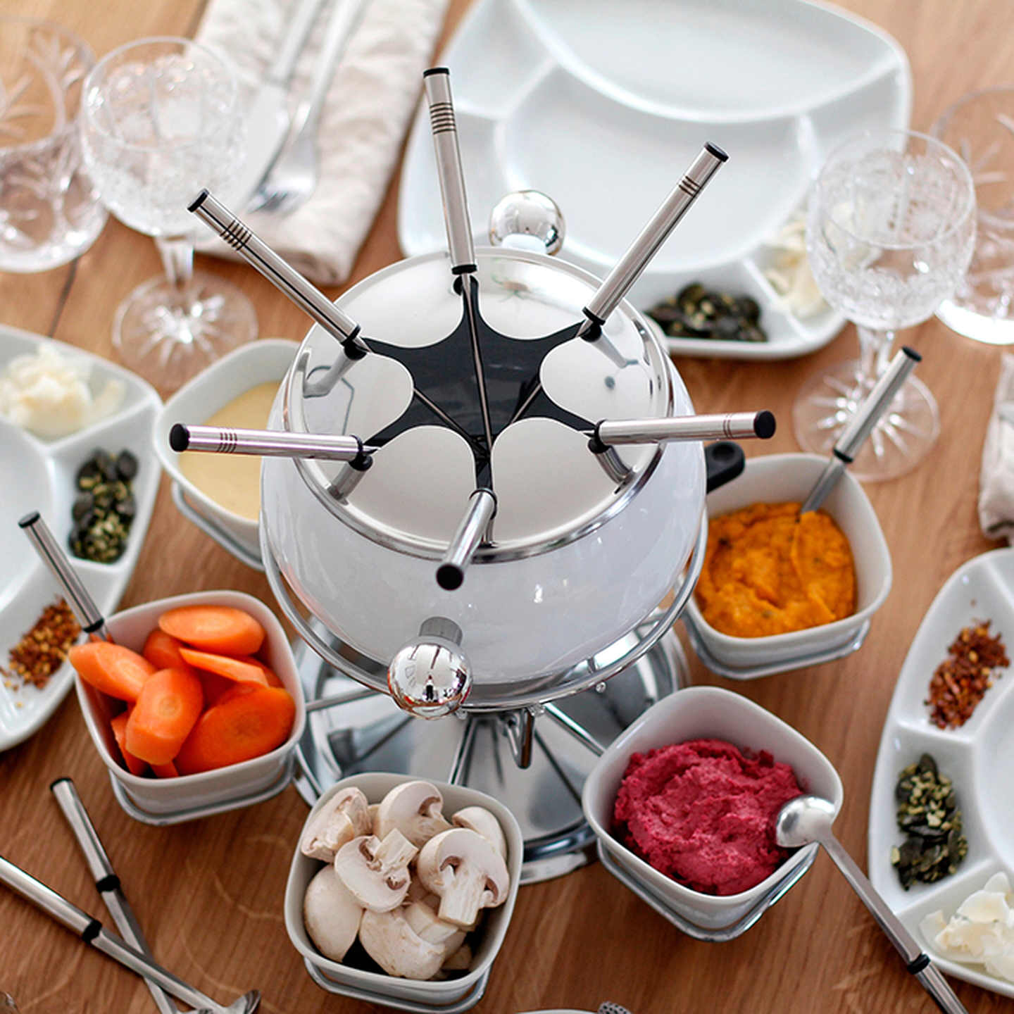 Ein Fondue Set auf einem gedeckten Tisch mit Aufstrichen und Gemüse