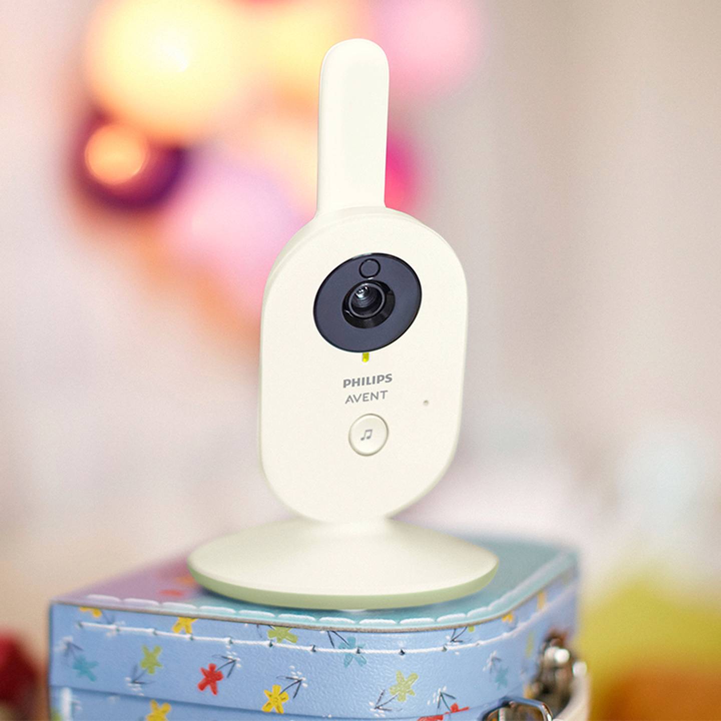 Eine weiße Philips Avent Babyphone-Kamera mit Antenne, platziert auf einem bunten, gemusterten Karton mit verschwommenem Hintergrund.