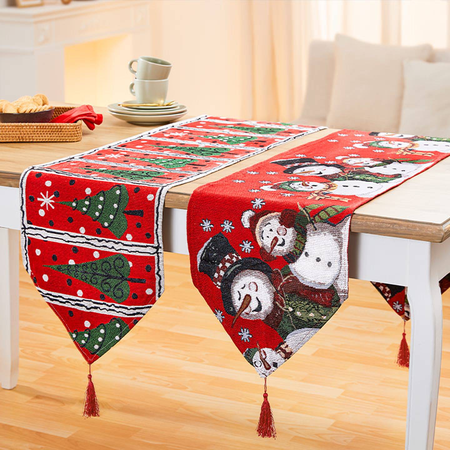 Festliche Tischläufer mit Schneemann- und Weihnachtsbaummotiven auf einem Holztisch, mit Quasten an den Enden.