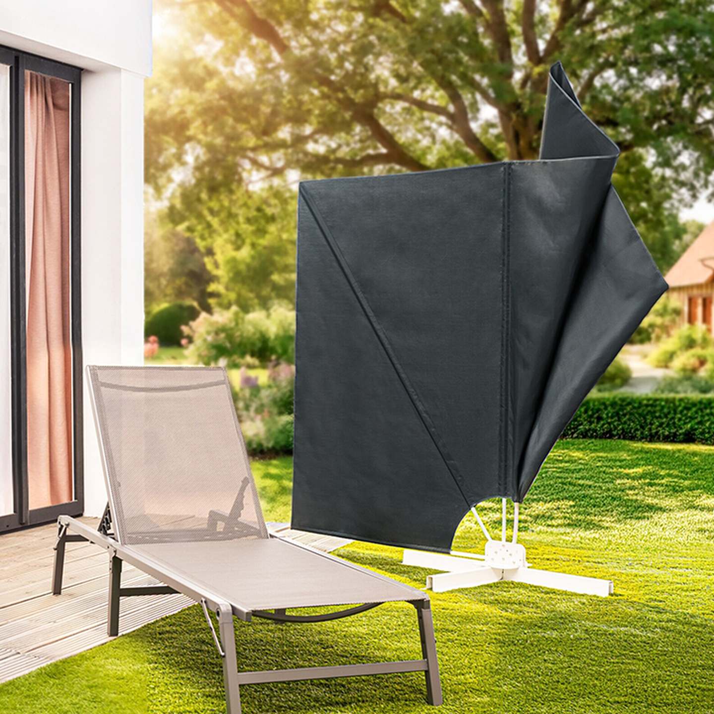 Ein Sonnenschirm und eine Sonnenliege auf einer Holzterrasse in einem sonnigen Garten, mit üppiger Vegetation und einem Haus im Hintergrund.