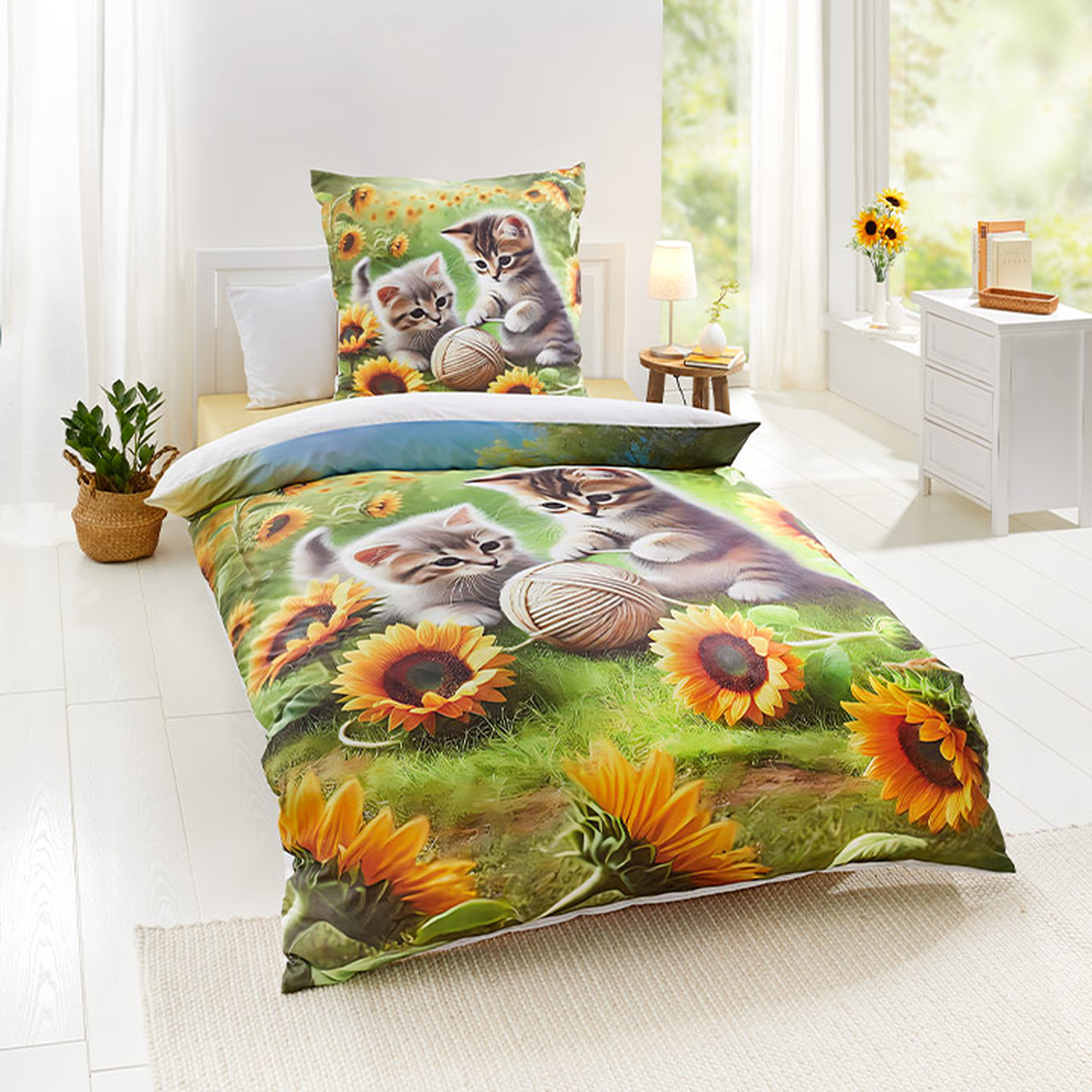 Bettwäscheset mit verspieltem Kätzchen- und Sonnenblumen-Design in einem hellen, sonnendurchfluteten Raum mit weißen Möbeln und einem Korb voller Pflanzen.