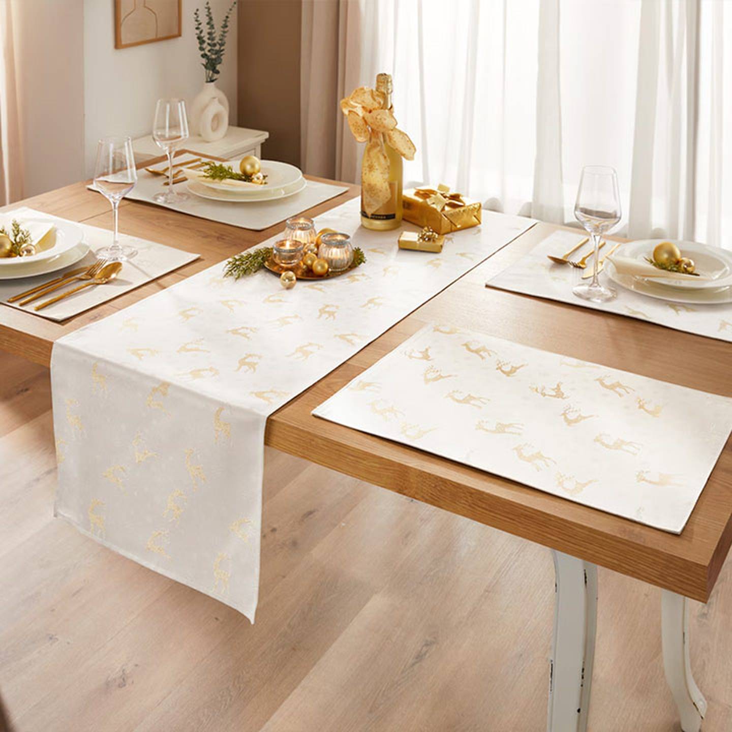 Elegante Essgruppe mit weiß-goldenem Tischläufer und Platzsets, Weingläsern, goldenem Besteck und dekorativen Ornamenten.