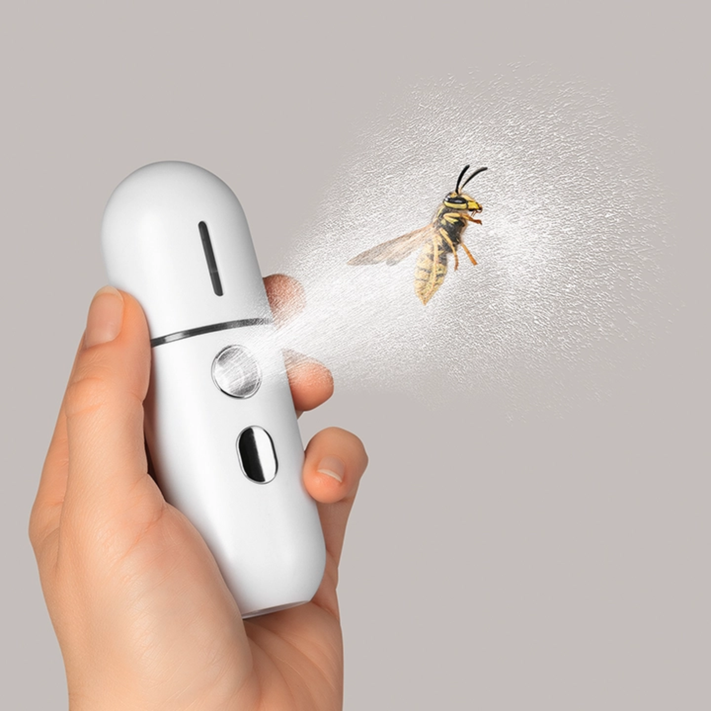 Eine Hand, die ein weißes Sprühgerät hält, das auf eine Wespe gerichtet ist, während ein Sprühnebel herausströmt.