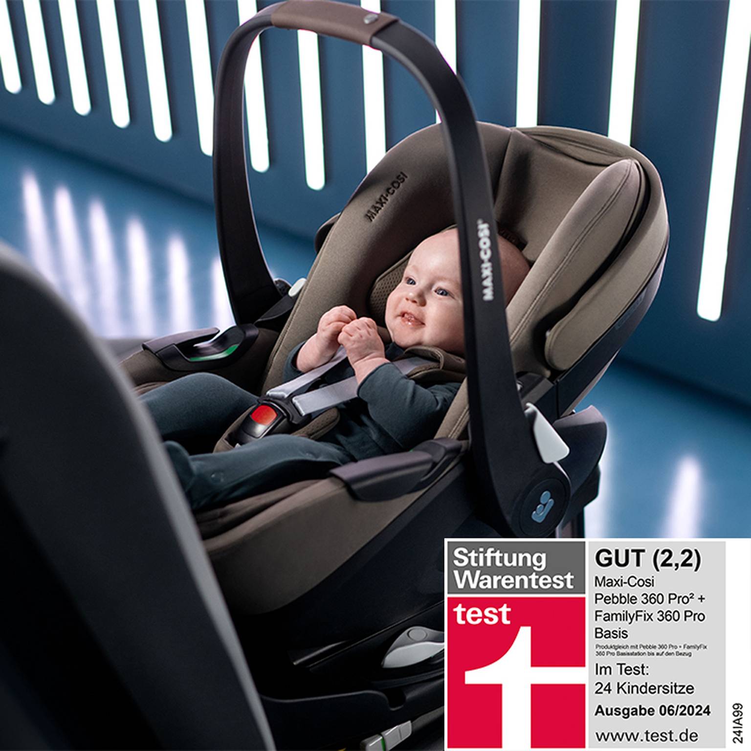 Ein Baby sitzt in einem Maxi-Cosi Autositz. Ein Etikett zeigt eine Testbewertung und Angaben der Stiftung Warentest.