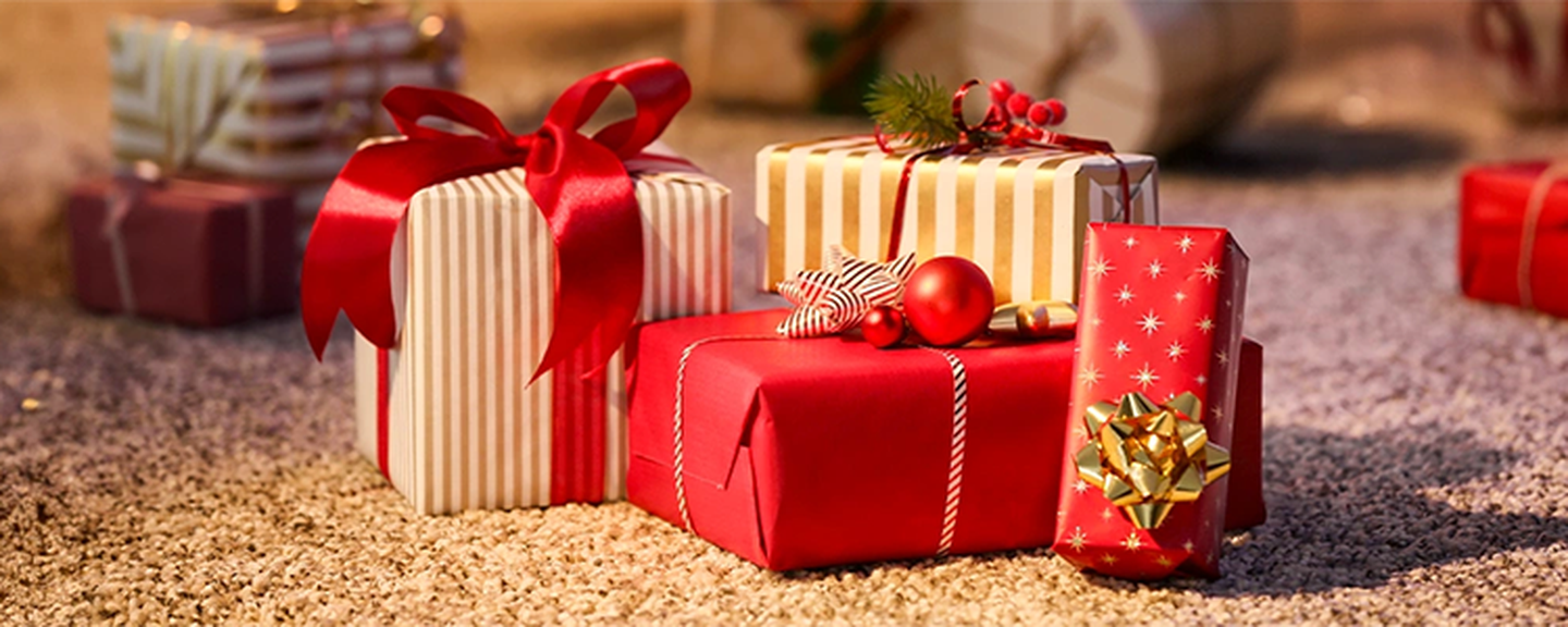 Mehrere mit rot gestreiftem Papier verpackte Geschenke, verziert mit Schleifen und Ornamenten, liegen auf einem Teppichboden.