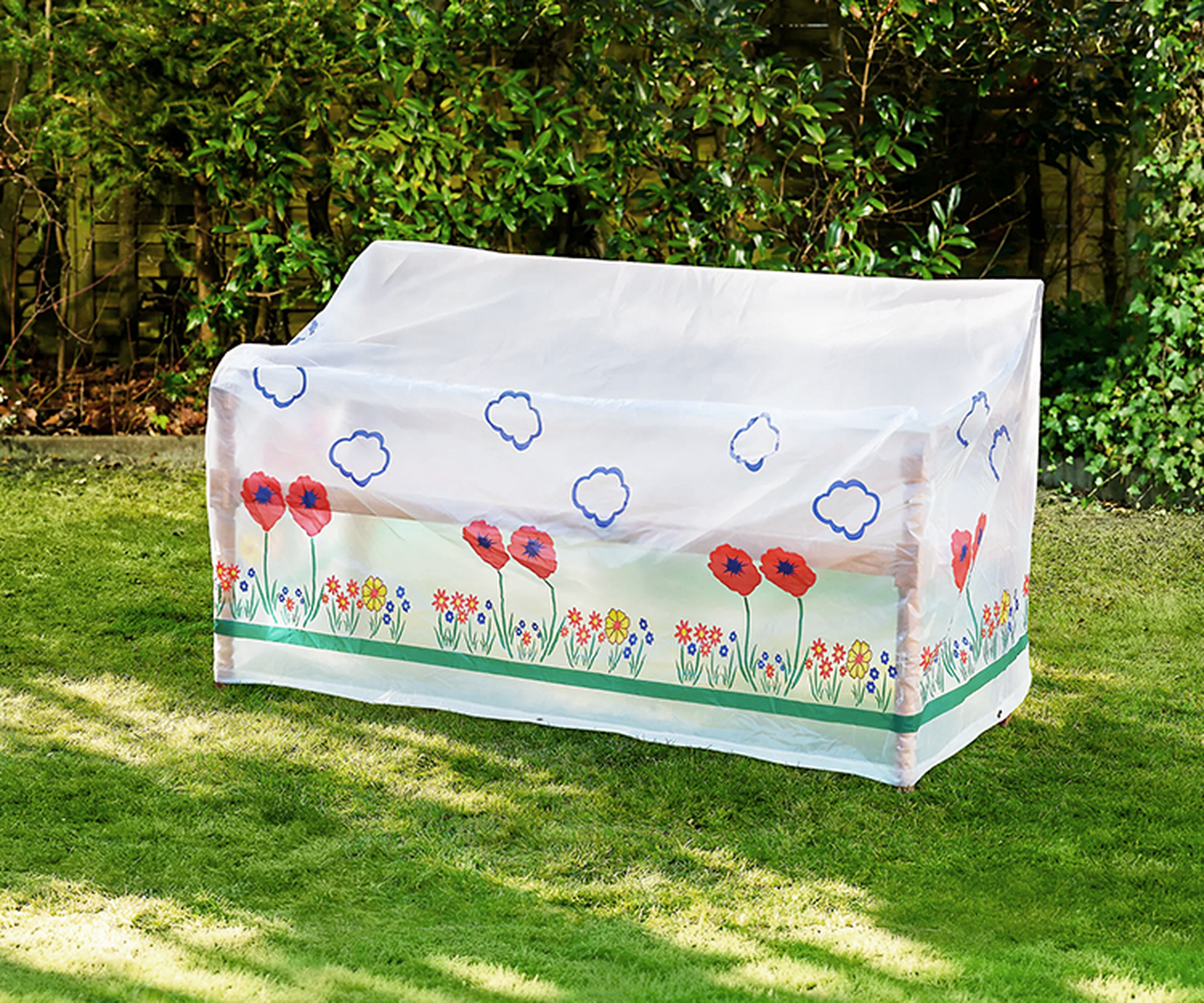 Eine Gartenbank ist mit einer dekorativen Plane bedeckt, auf der rote Mohnblumen, bunte Blumen und blaue Wolken auf einem üppig grünen Rasen abgebildet sind.