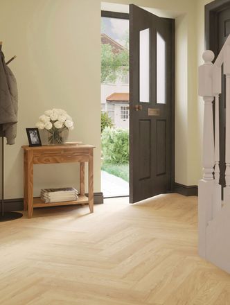 Sandy-coloured wood-effect floor planks in a parquet laying pattern in a hallway