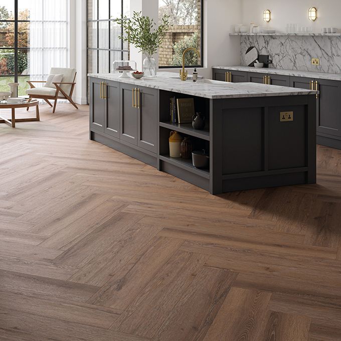 Brown wood-effect flooring planks in herringbone laying pattern in an open plan kitchen