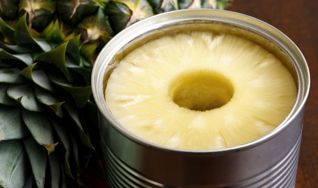 Ananas in einer Konservendose neben einer frischen Ananas