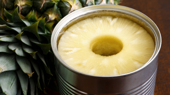 Ananas in einer Konservendose neben einer frischen Ananas