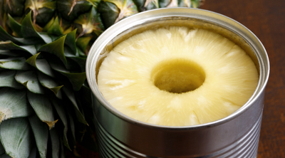Ananas in einer Konservendose neben einer frischen Ananas