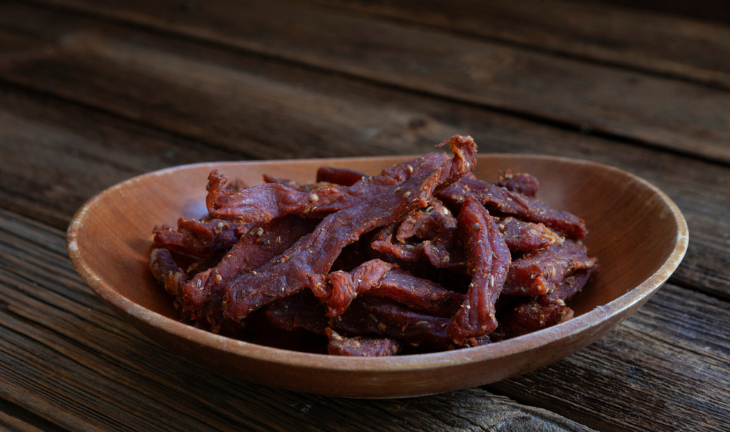 Trockenfleisch, das in dünnen Streifen in einer Holzschale liegt.