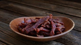 Trockenfleisch, das in dünnen Streifen in einer Holzschale liegt.