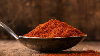 Leuchtend rotes Paprikapulver auf einem Metall-Löffel