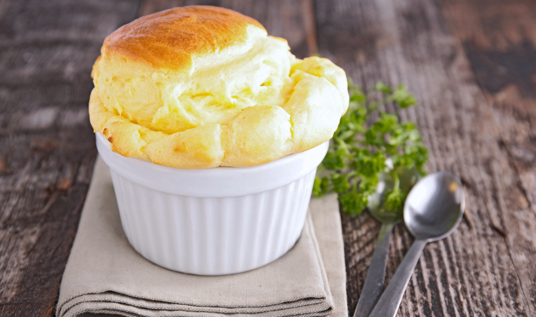 Ein luftiges Soufflé in einer geriffelten, weißen Souffléform aus Porzellan