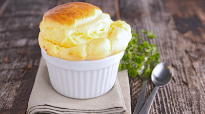 Ein luftiges Soufflé in einer geriffelten, weißen Souffléform aus Porzellan