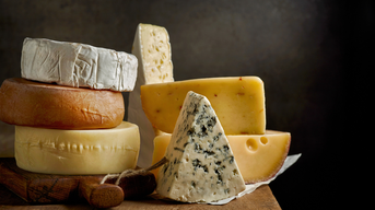 Unterschiedliche Käsesorten liegen gestapelt auf einem Holzbrett