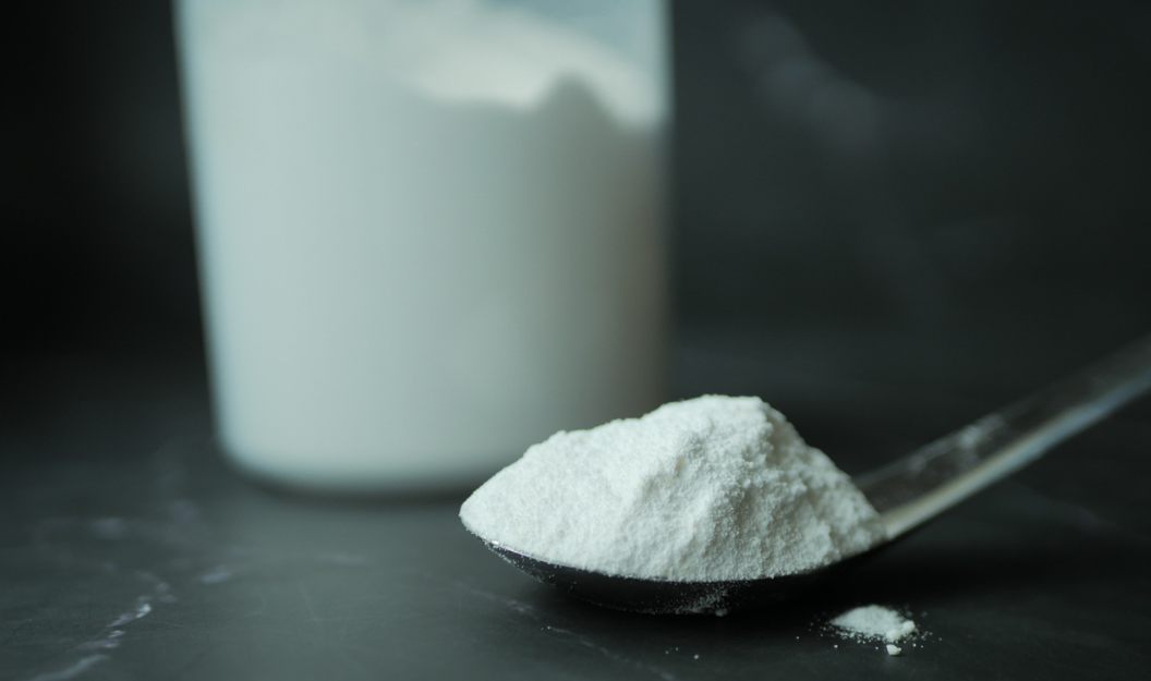 Carrageen-Pulver auf einem Löffel, im Hintergrund ein Behälter mit mit Pulver