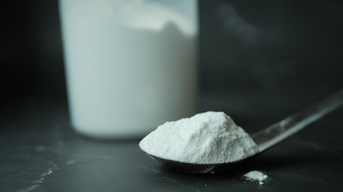 Carrageen-Pulver auf einem Löffel, im Hintergrund ein Behälter mit mit Pulver