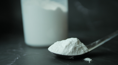 Carrageen-Pulver auf einem Löffel, im Hintergrund ein Behälter mit mit Pulver