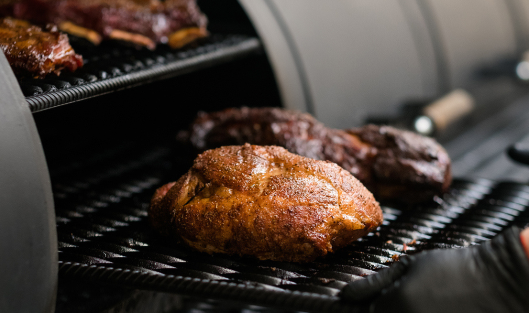Verschiedene saftige und marinierte Fleischstücke liegen auf einem Grillrost.