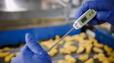 Kontrolle der Produkttemperatur mithilfe eines professionellen Thermometers bei der Lebensmittelproduktion.