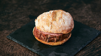 Ein saftiges Stück Leberkäse mit einer goldbraunen Kruste im Brötchen.