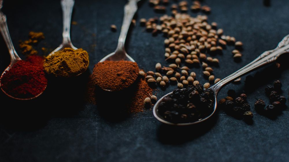 Teelöffel voller Gewürze wie Pfeffer, Paprika und Curry