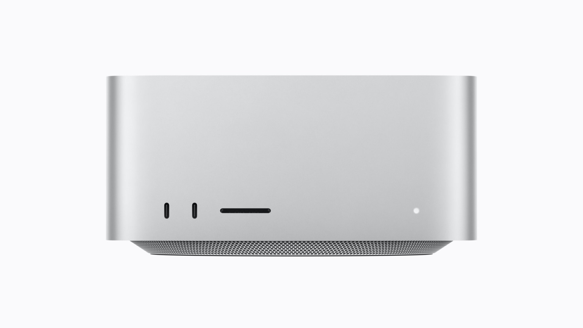 A silver, compact Mac Studio viewed from the front, featuring slots, ports, and a small LED indicator on a smooth surface.