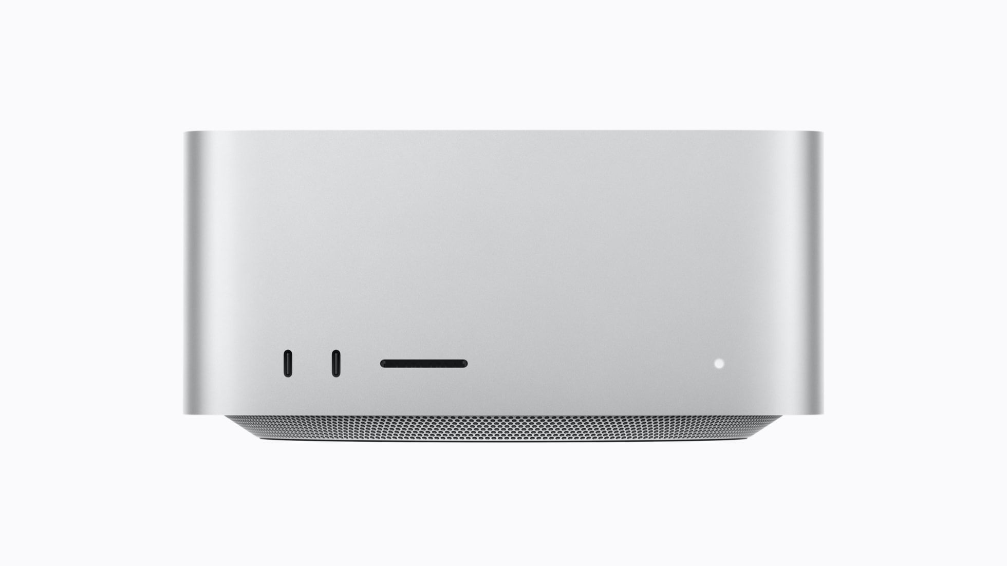 A silver, compact Mac Studio viewed from the front, featuring slots, ports, and a small LED indicator on a smooth surface.