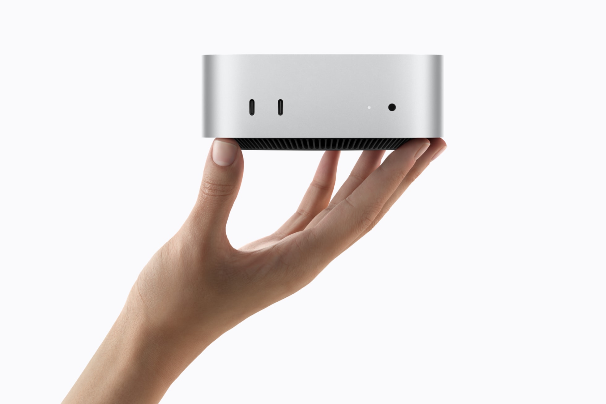 A hand holding a small, sleek, silver electronic device with ports visible on the front, against a white background.