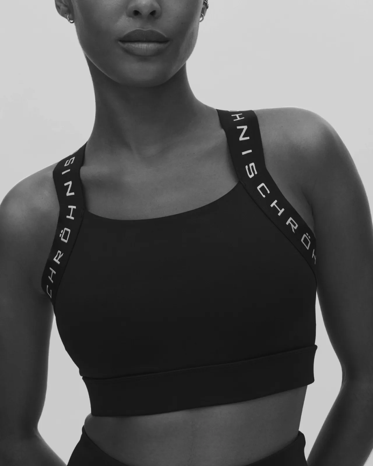 Person wearing a black sports bra with branded straps, against a plain background.