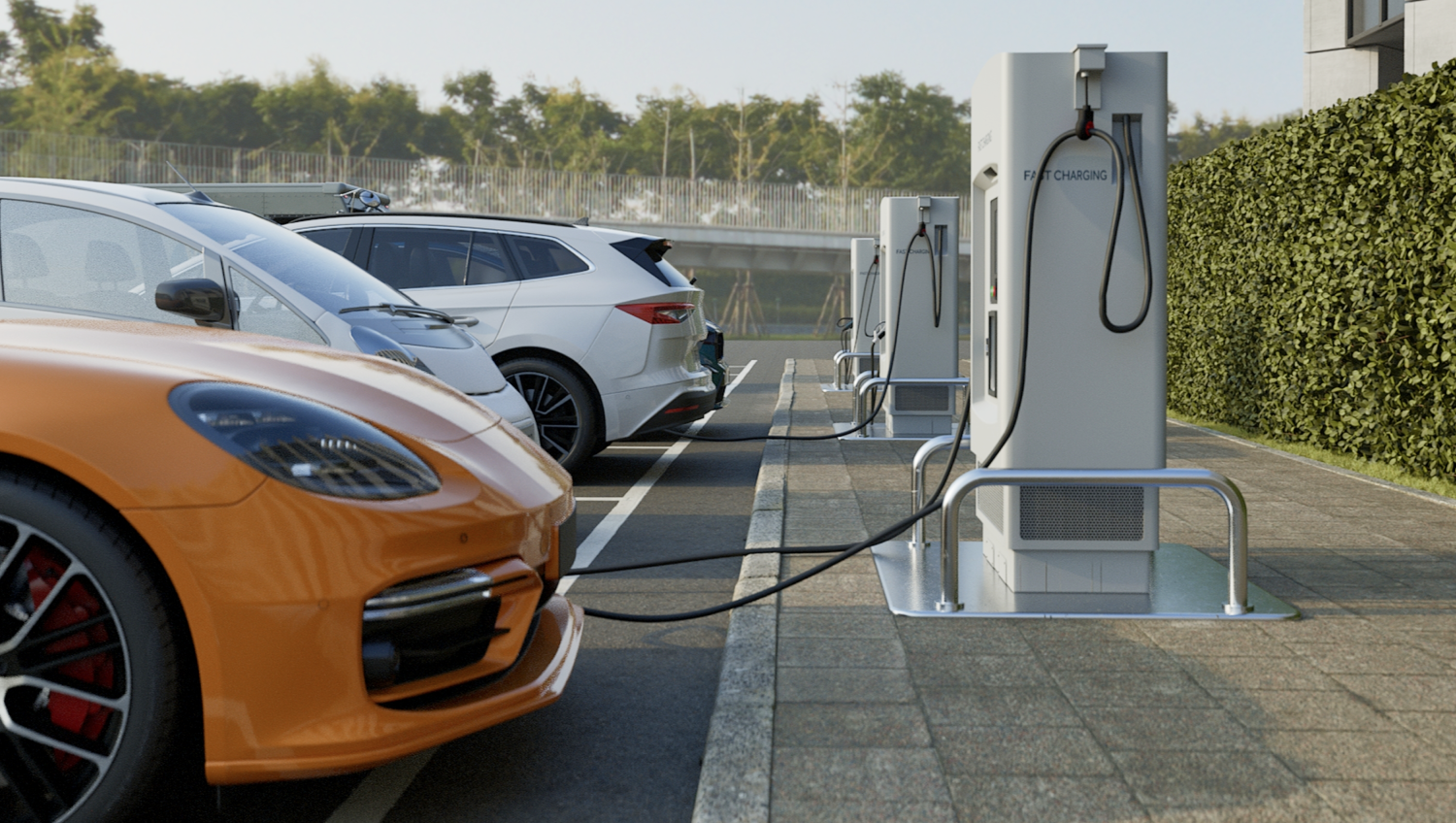 Orangenes E-Auto wird an einer Ladesäule auf einem Parkplatz geladen.