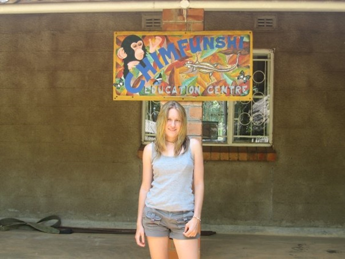 A woman standing in front of the sign 'Chimfunshi Education Centre.'