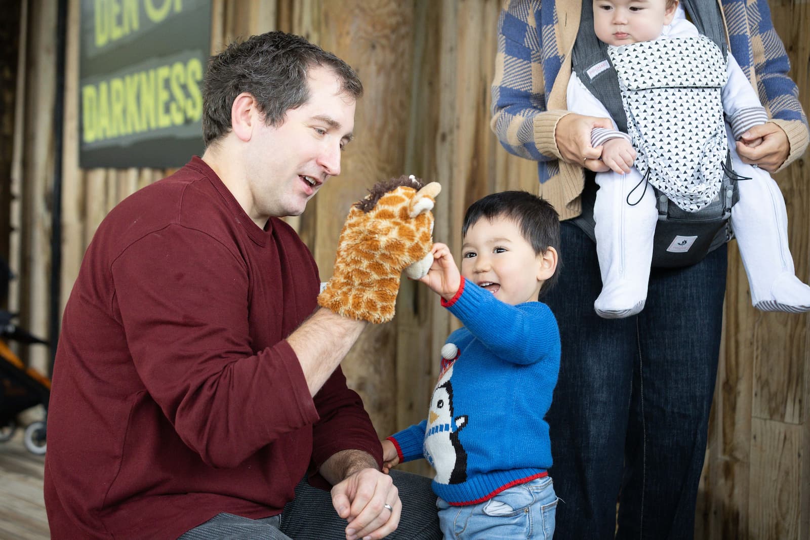An adult and child interact with a giraffe puppet